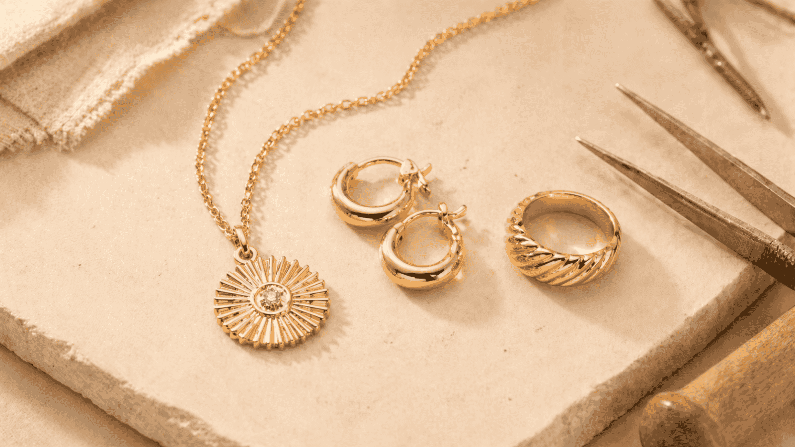 Close-up of gold plated stainless steel jewelry manufacturing process showing 316L base metal pieces and 18K gold plating finish on clean workshop surface