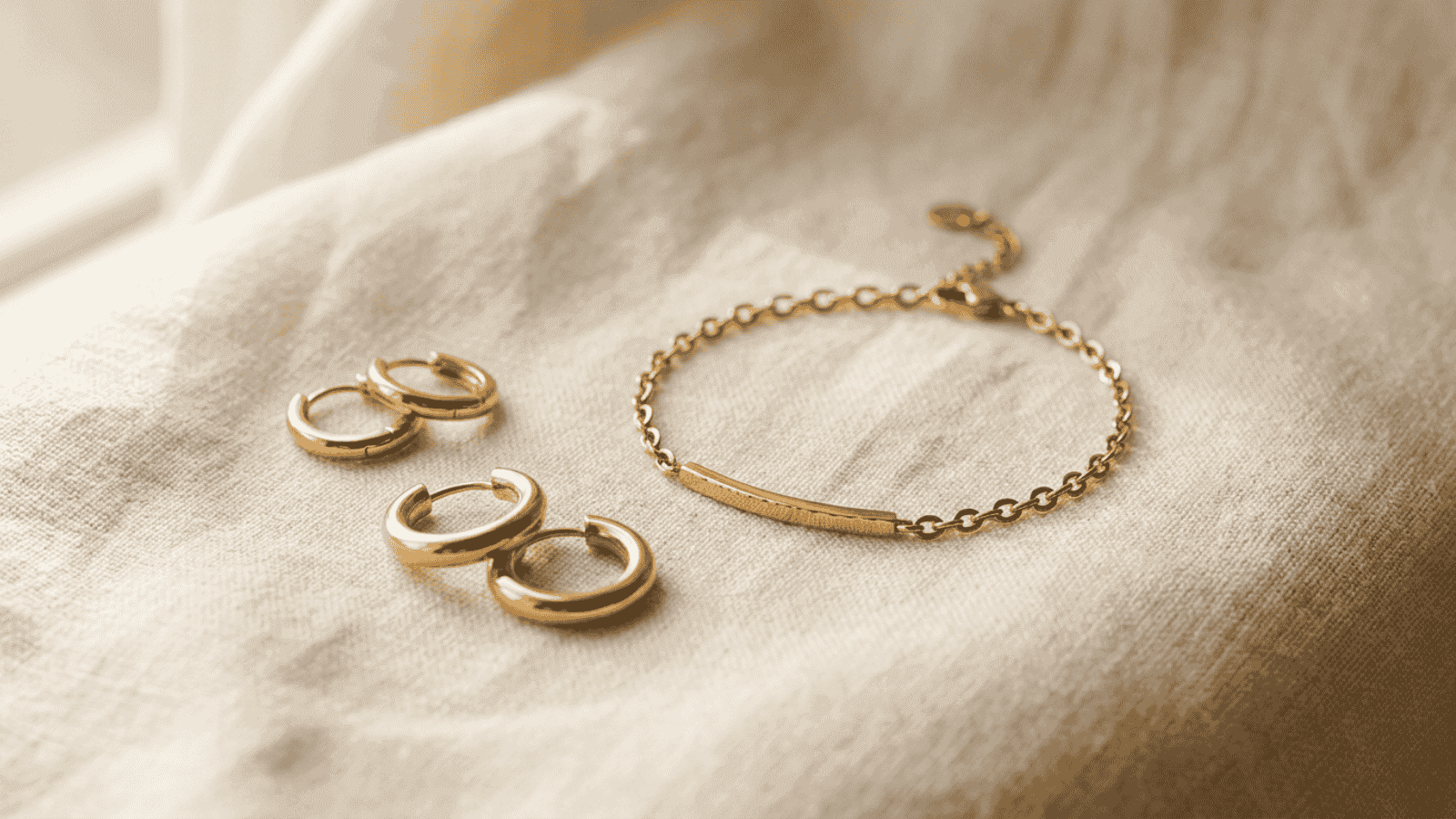Close-up of stainless steel gold plated jewelry pieces against a soft cream background showing hypoallergenic jewelry suitable for sensitive skin