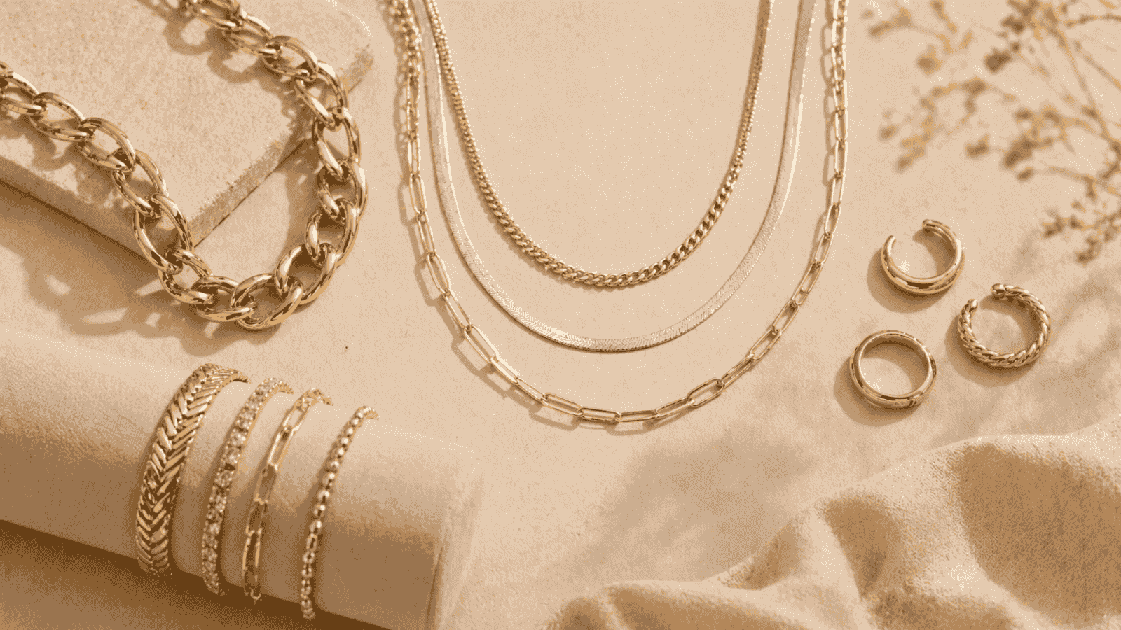 Curated display of 2026 jewelry trends including chunky gold chains, mixed metal layered necklaces, and adjustable rings styled on cream background with Toronto aesthetic