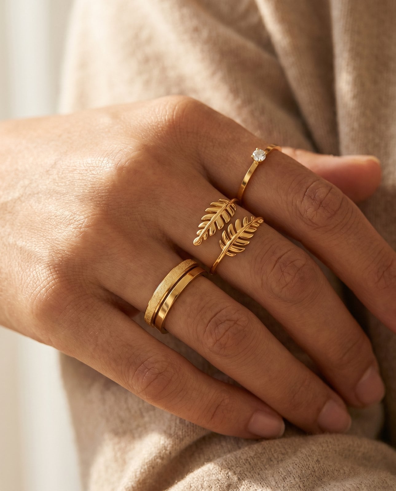 Model's hand wearing stacked minimalist gold plated rings including an open-back adjustable band