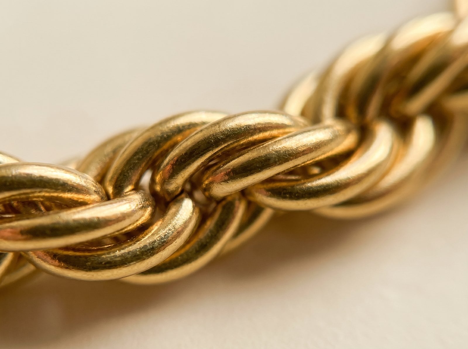 Extreme macro of a single 18K gold-plated chain link showing the warm even richness of the plated finish