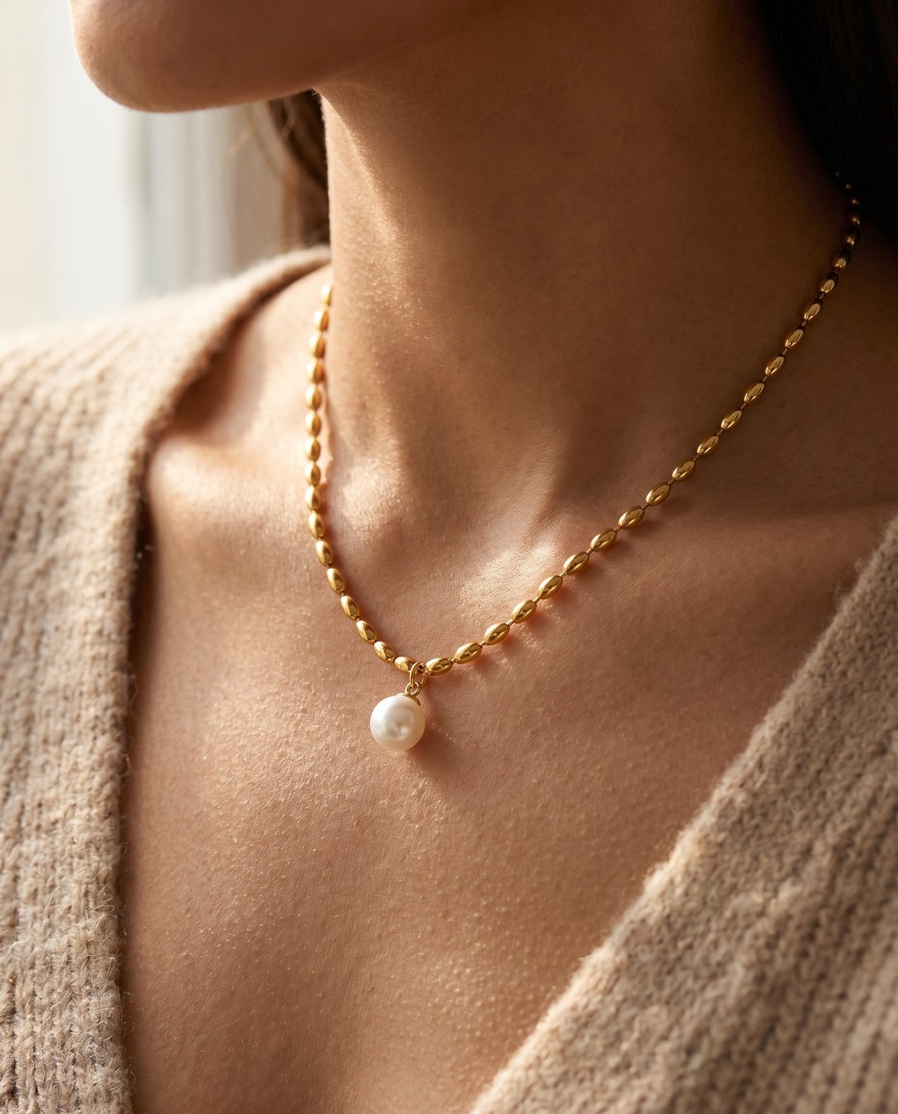 Warm-neutral-skinned woman wearing a dainty 18K gold-plated pendant necklace at the collarbone in daily wear