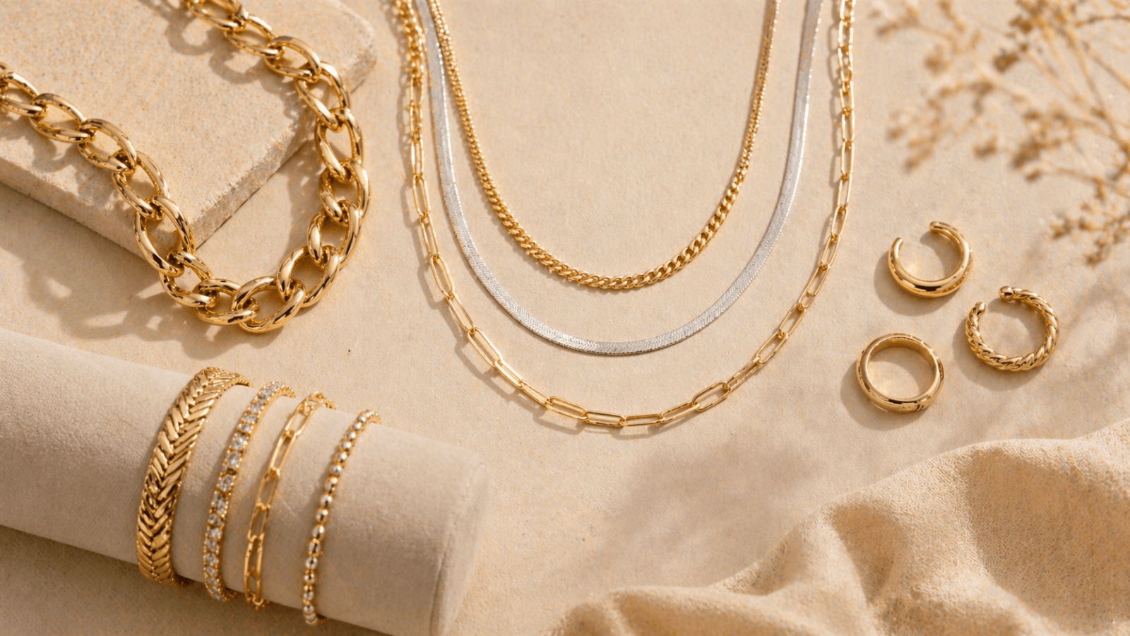 Curated display of 2026 jewelry trends including chunky gold chains, mixed metal layered necklaces, and adjustable rings styled on cream background with Toronto aesthetic