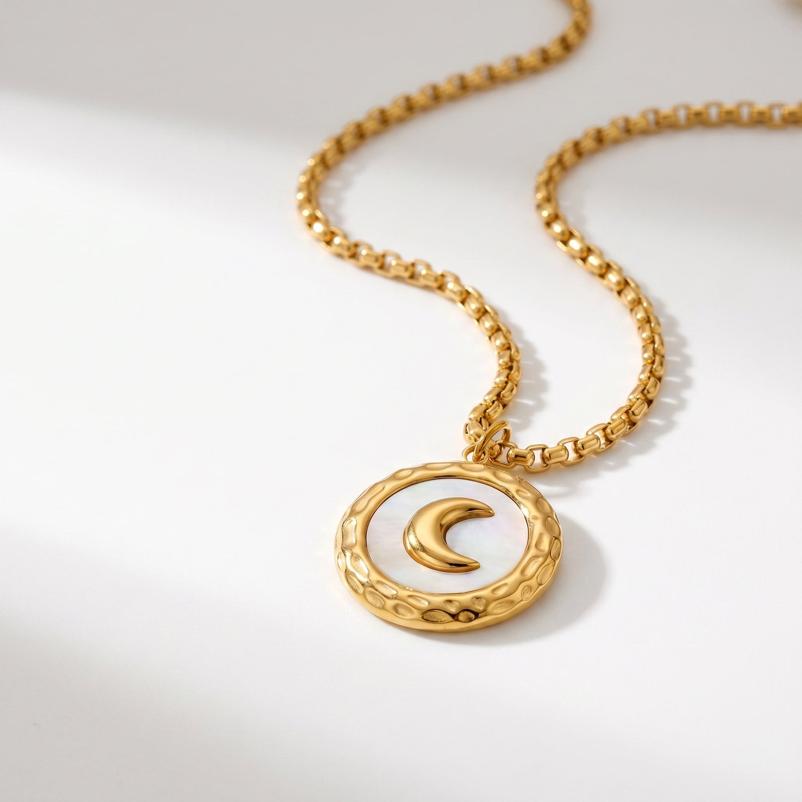 A single dainty gold-plated cable-chain necklace with a small pendant curved on a clean white studio surface.