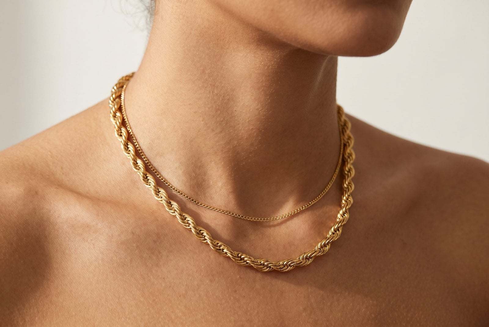 Warm-neutral-skinned model wearing a delicate 18K gold-plated layered chain necklace on her collarbone