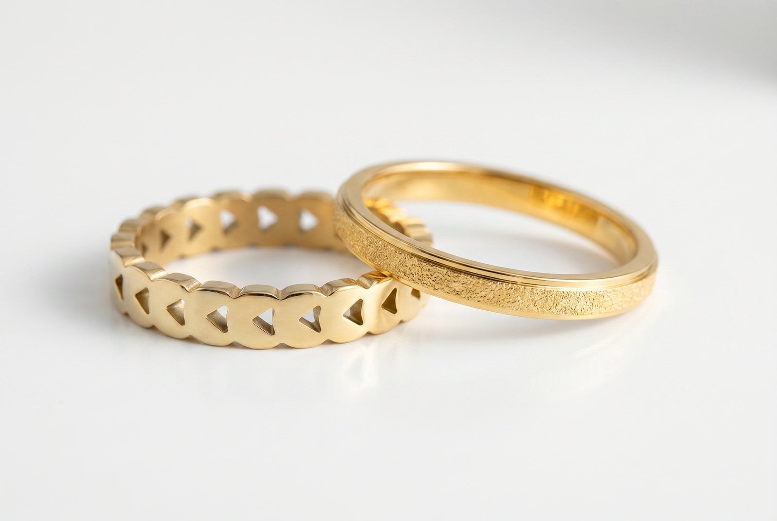 Two thin gold-plated stacking rings touching on white, warmer 18K beside a paler cooler 14K tone