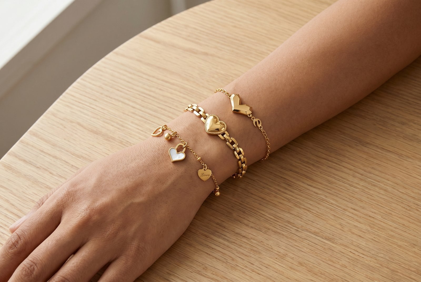Forearm resting flat with a gold-plated stack ordered from thin chain at the wrist to thicker pieces up the arm