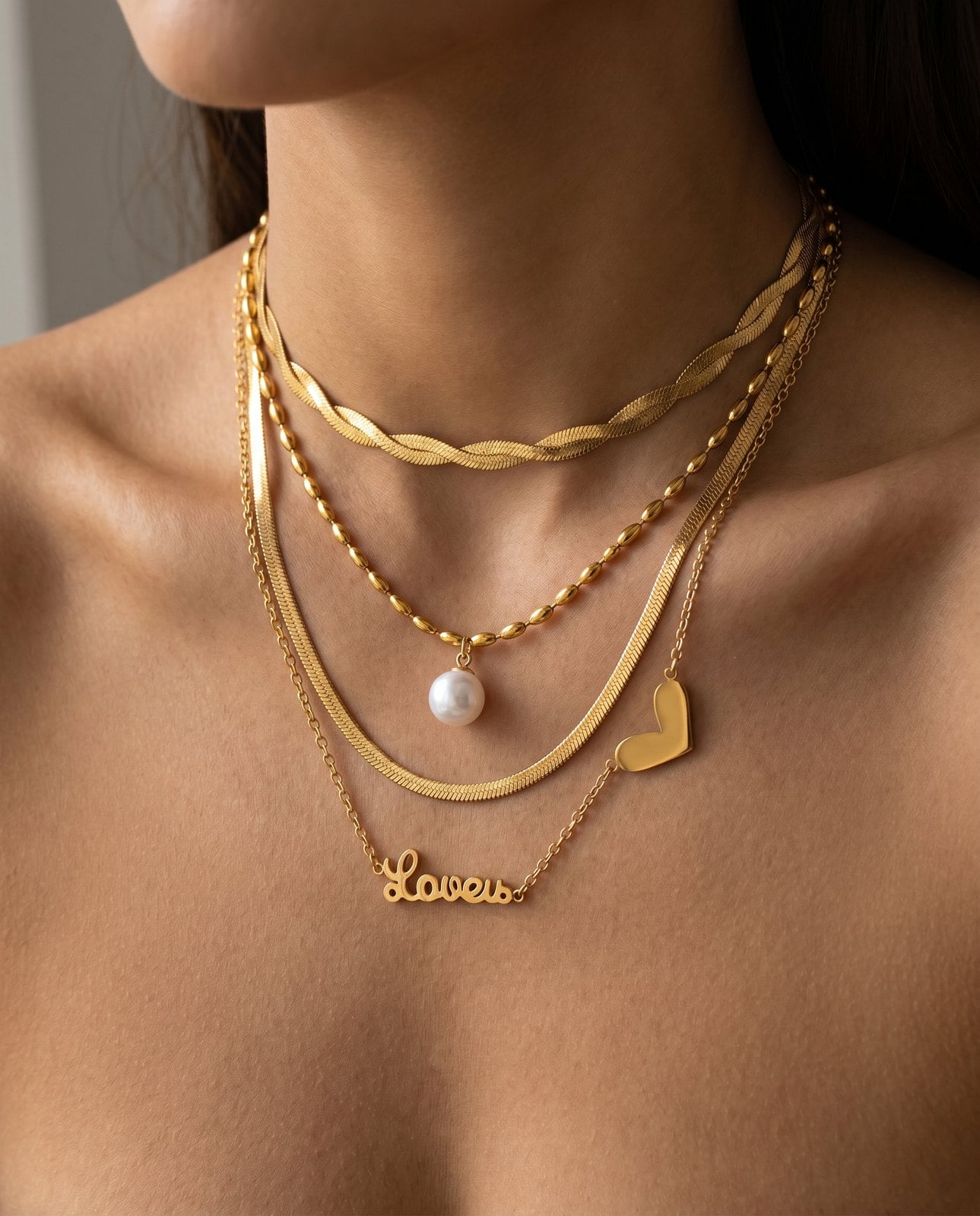 Close-up of layered gold necklaces at three lengths on a collarbone with even vertical spacing between chains
