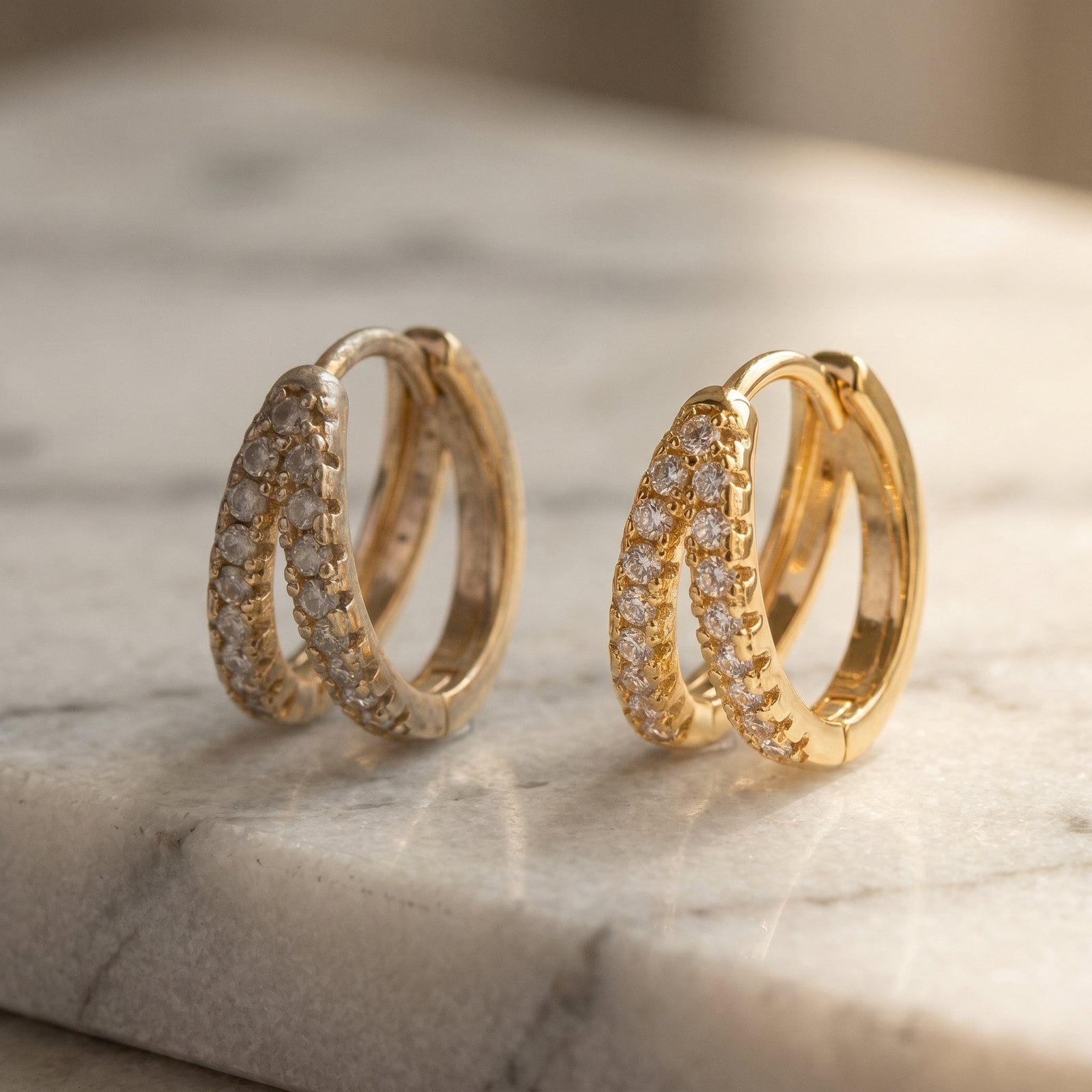Two matching gold plated hoop earrings on marble, one dull and one freshly cleaned to a soft shine