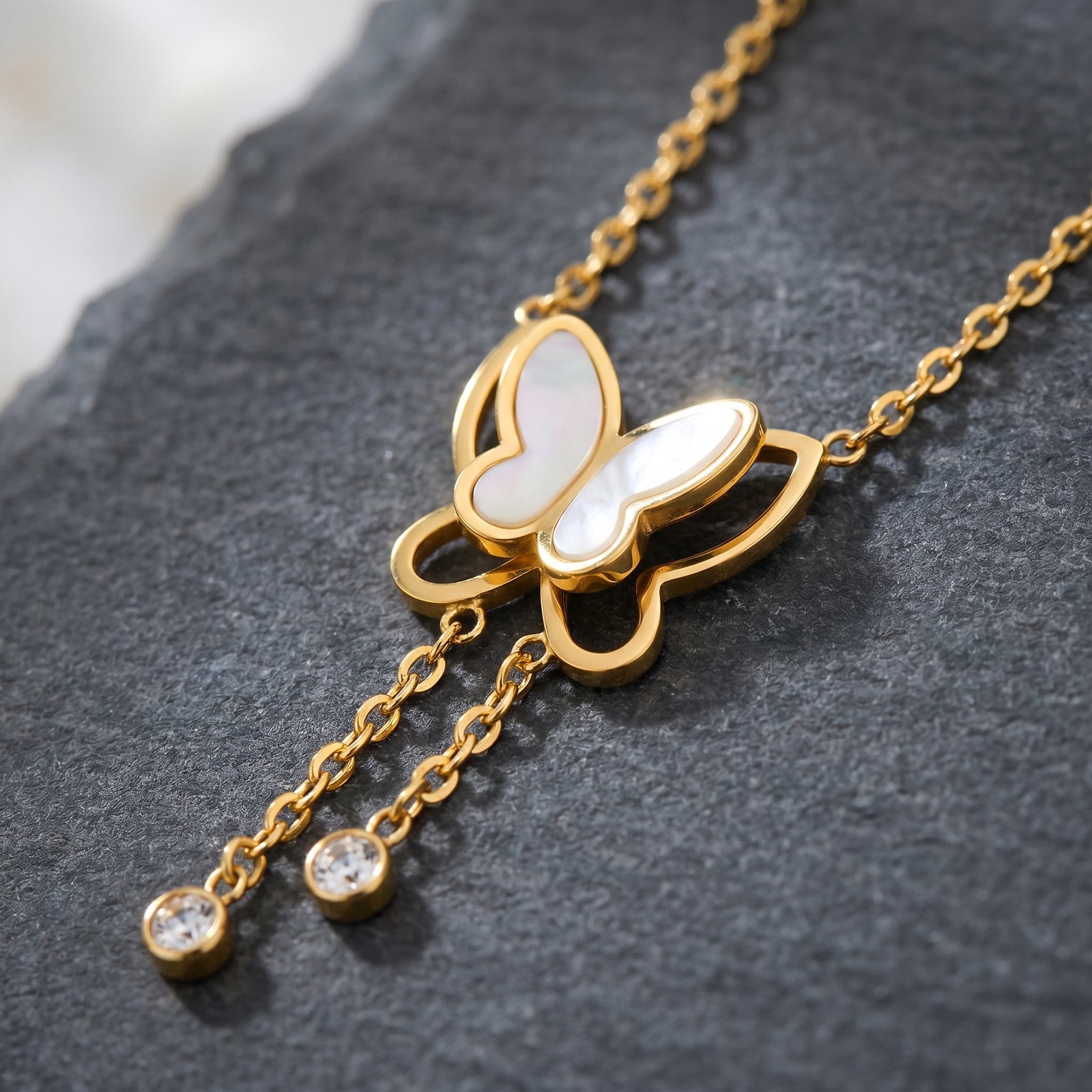 Extreme macro of a delicate gold-plated butterfly pendant resting on dark stone