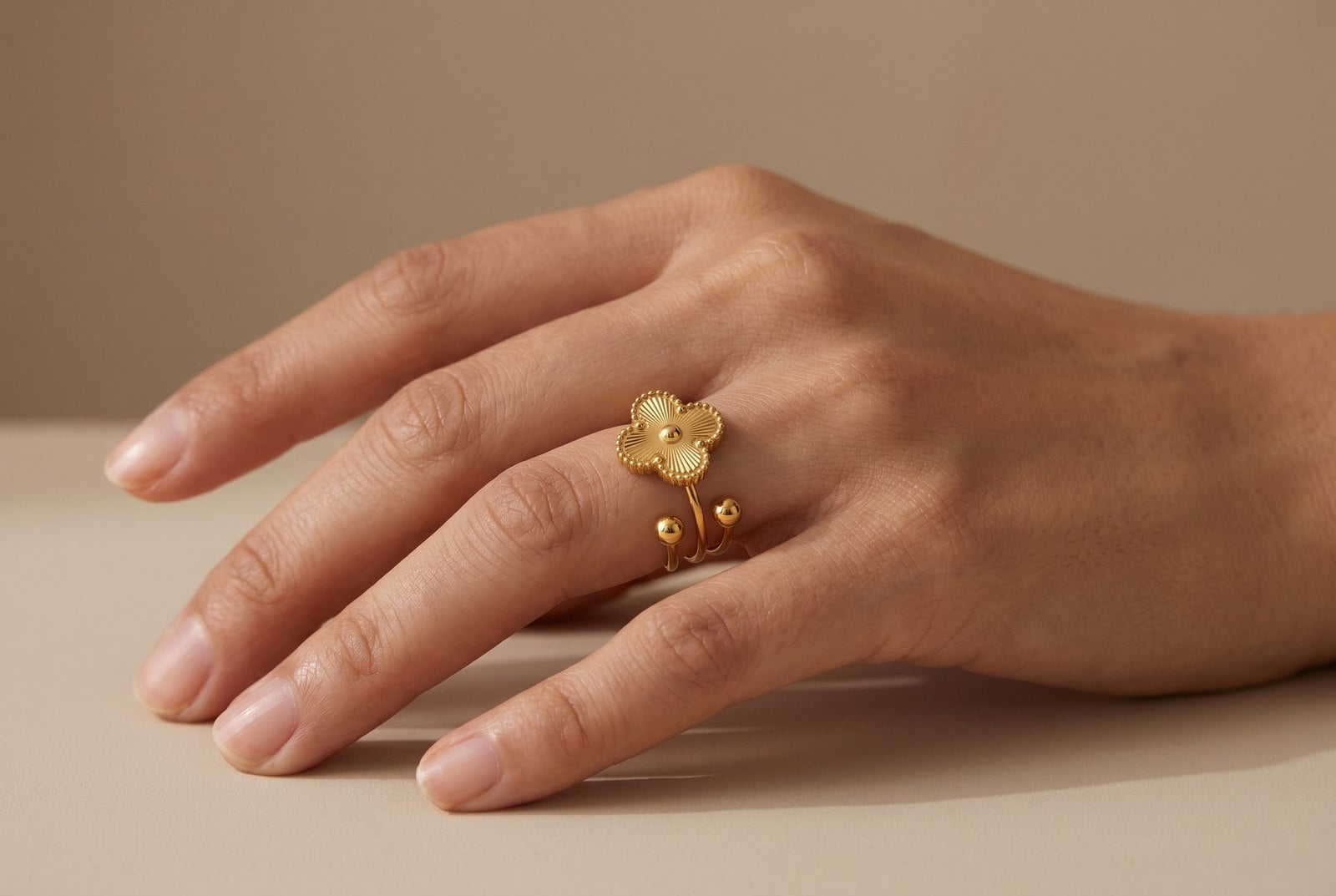 Woman's hand wearing a gold-plated four-leaf clover adjustable ring, soft natural light