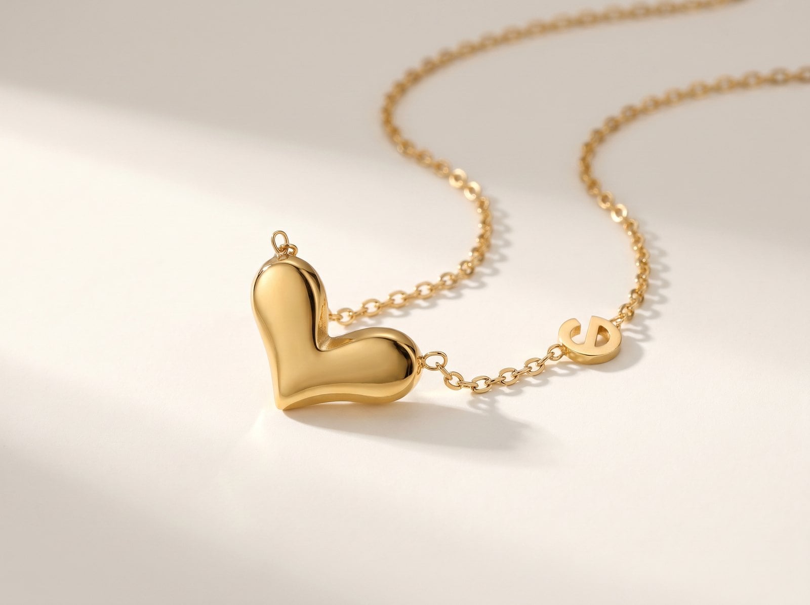 Small dainty gold-plated heart pendant on a fine chain photographed on a warm-white background