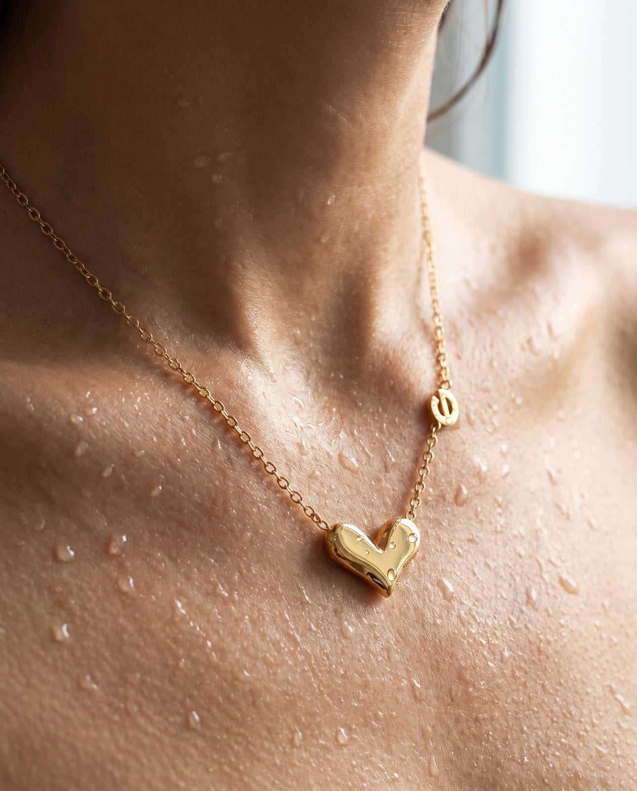 Delicate gold chain on wet collarbone skin with water droplets, illustrating everyday waterproof wear