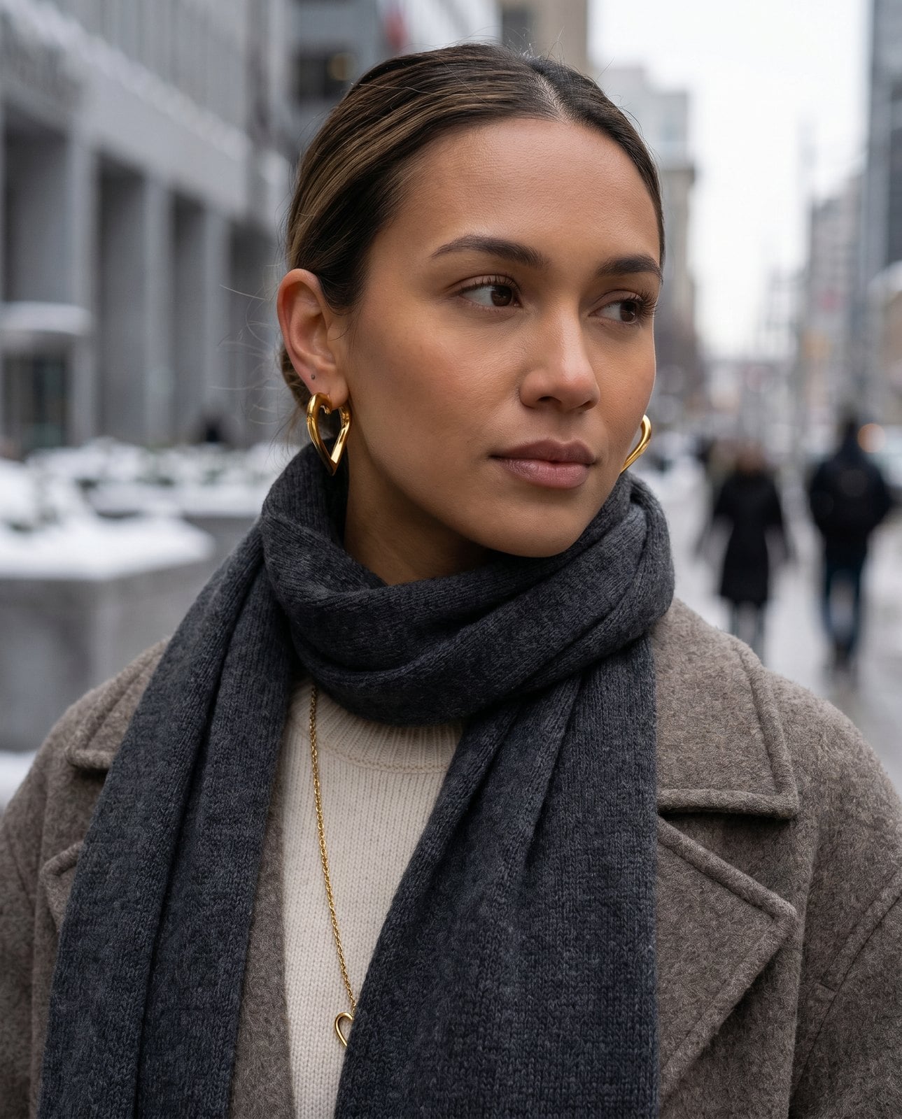Woman on a wintry Toronto street with hair back showing gold hoops above a scarf and coat collar