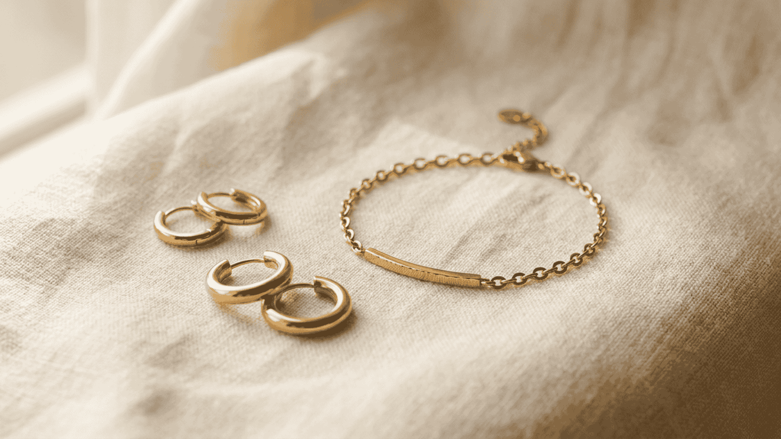 Close-up of stainless steel gold plated jewelry pieces against a soft cream background showing hypoallergenic jewelry suitable for sensitive skin