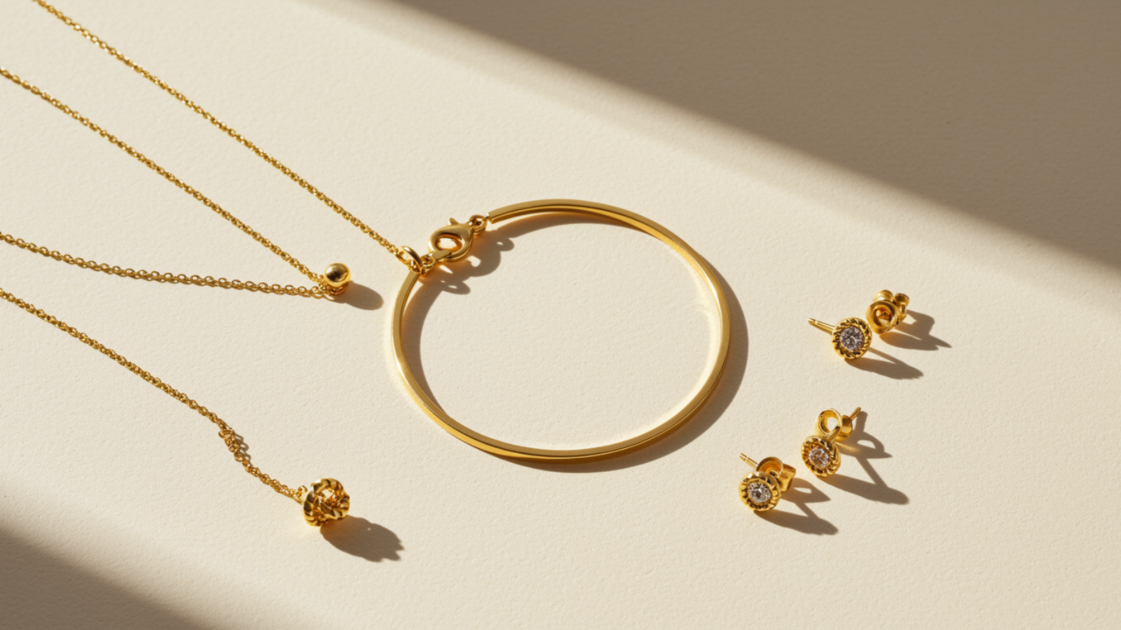 Elegant 18K gold plated jewelry arrangement including necklace, bracelet, and earrings on a soft neutral background